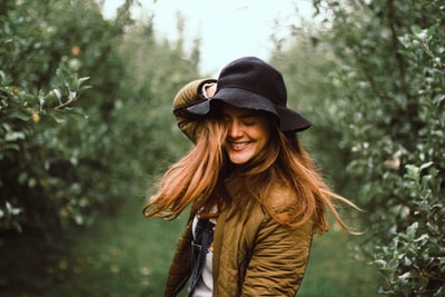 选择聚焦摄影的女人微笑着握住她的帽子
